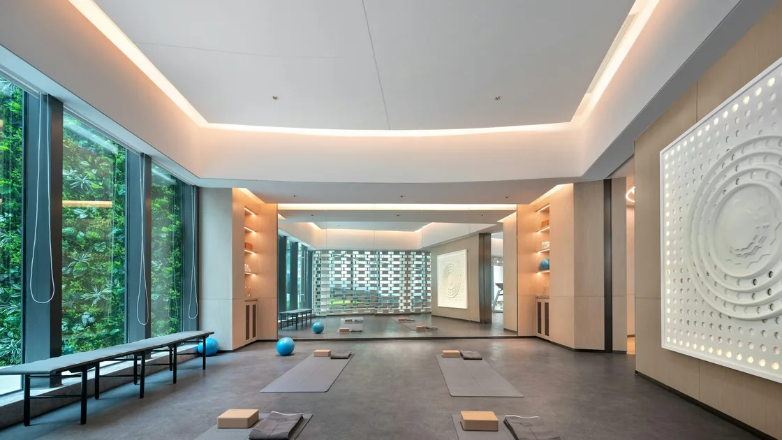 Sala de yoga vacía con esterillas extendidas, bloques y luz natural entrando por los ventanales